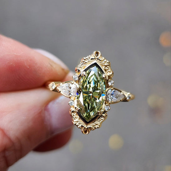 Fairy green marquise moissanite engagement ring Odette with gold scroll side band and diamond accents 14k yellow gold vintage inspired artisan fine jewelry made in portland oregon