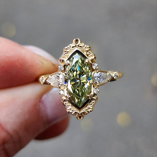 Fairy green marquise moissanite engagement ring Odette with gold scroll side band and diamond accents 14k yellow gold vintage inspired artisan fine jewelry made in portland oregon