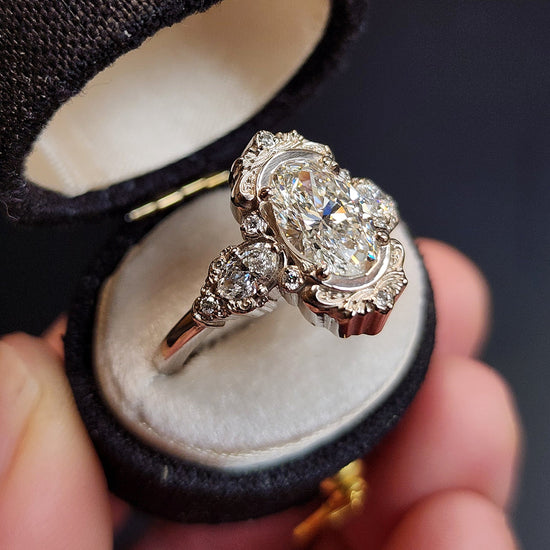 josephine engagement ring with 1.70 carat oval lab diamond center stone and oval diamond sides vintage inspired scrolling gold wedding ring